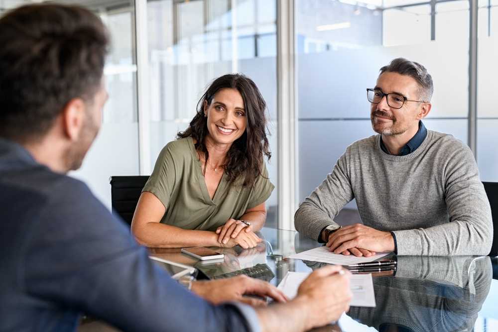 A smiling couple talking to a financial advisor.